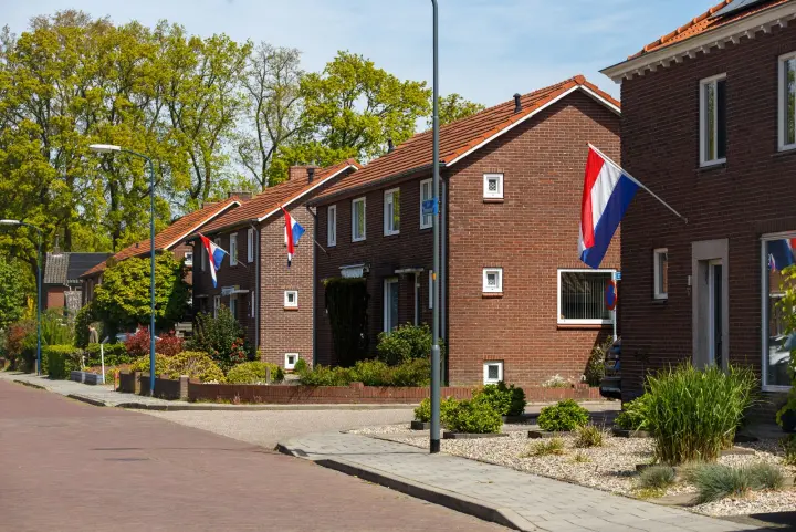 Een Nederlandse woonstraat met bakstenen rijtjeshuizen en vlaggen